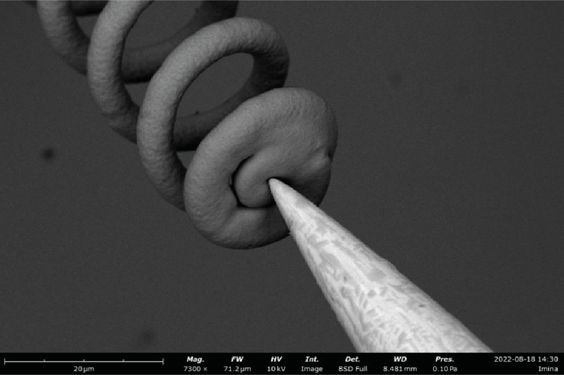 A 3D-printed metallic microspring is compressed by a miBot nanoprober tip inside a Phenom tabletop electron microscope.