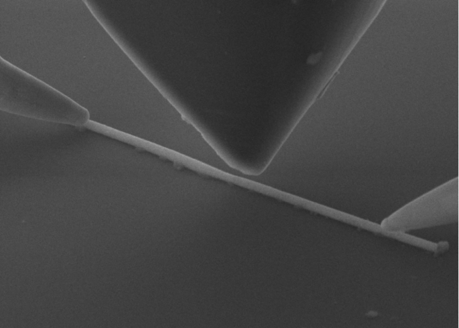 Nano probers and a nanoindentor in contact with a metal line inside an SEM to measure transport change upon indentation.